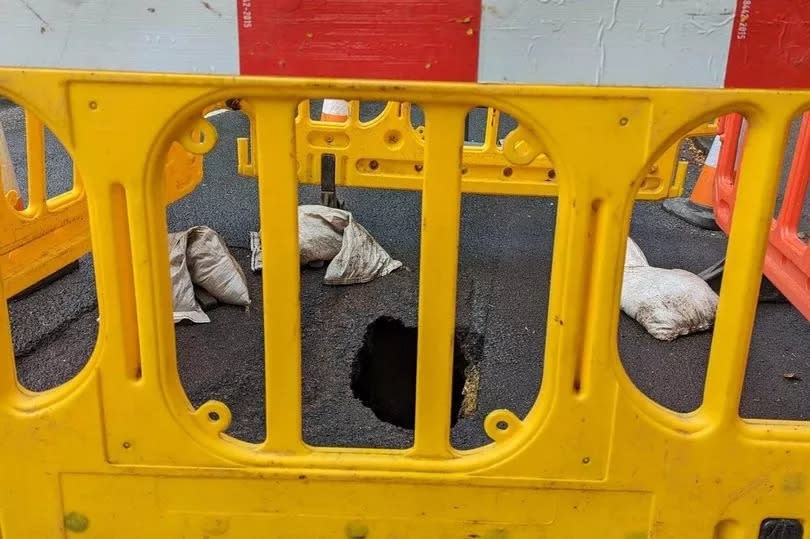 Barriers weighed down by sandbags, along with a sign and some cones were shielding the sinkhole from vehicles and people