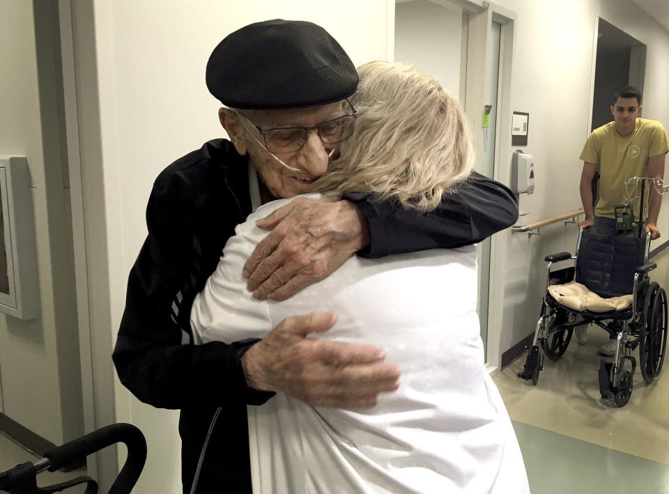 The Rev. John Sabbagh, left, and his son Ebby Sabbagh hugs nurse practitioner Kim O'Riley, Friday, Sept. 7, 2018 in Gilbert, Ariz. Thirty-five years after a Mesa man cared for his son when he was shot in their native Lebanon, the son is returning that devotion. Both the Rev. John Ibraham Sabbagh and his 54-year-old son, Ebby Sabbagh, are celebrating one year of going strong since the elder Sabbagh received a crucial stem-cell transplant. (AP Photo/Terry Tang)