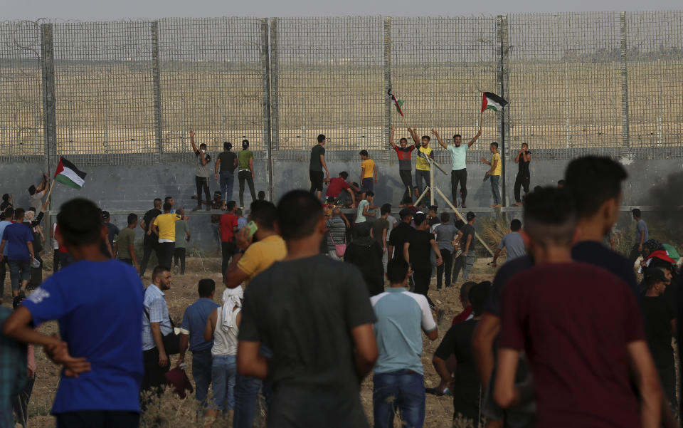 Protestors chant while try to climb the fence of the Gaza Strip's border with Israel, during a protest marking the anniversary of a 1969 arson attack at Jerusalem's Al-Aqsa mosque by an Australian tourist later found to be mentally ill, east of Gaza City, Saturday, Aug. 21, 2021. (AP Photo/Adel Hana)