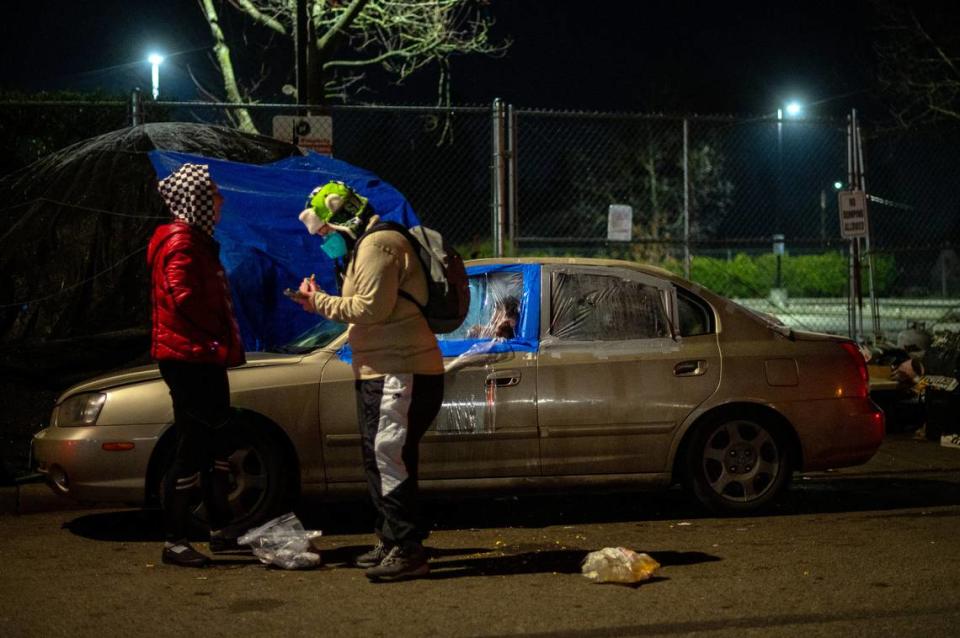 Sonja Nikiema, a Point in Time Count volunteer, talks with a person living out of their car on the side of East I Street in Tacoma, Wash., on Thursday, Jan. 27, 2022.