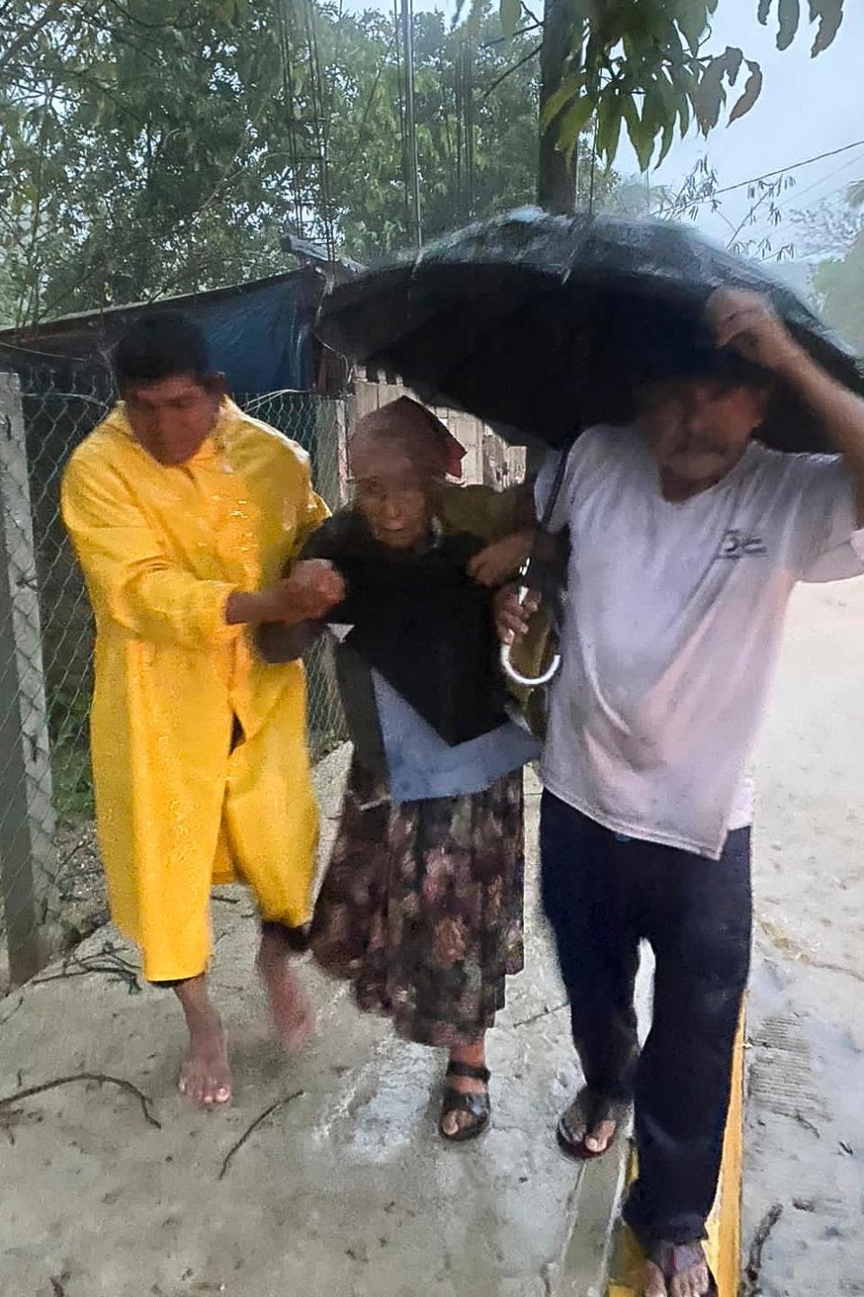 People try to take cover from the rain during the arrival of Hurricane Agatha in Huatulco, Oaxaca State, Mexico on May 30, 2022.  Hurricane Agatha, the first of the season, made landfall Monday near a string of beach resorts on Mexico's Pacific Coast, where residents and tourists hunkered down in storm shelters.