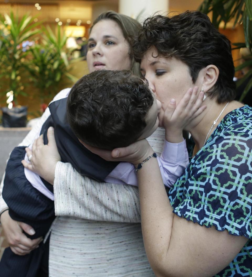 Nicole Yorksmith, right, kisses her three-year-old biological son while he is held by her spouse, Pam Yorksmith, during a news conference, Friday, April 4, 2014, in Cincinnati. Civil rights attorneys are arguing in Federal Court on Friday that a federal judge should prohibit Ohio officials from enforcing the state's ban on gay marriage. (AP Photo/Al Behrman)