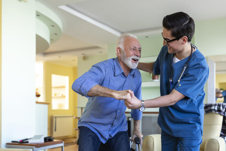 A certified nurse's assistant helping a man get up