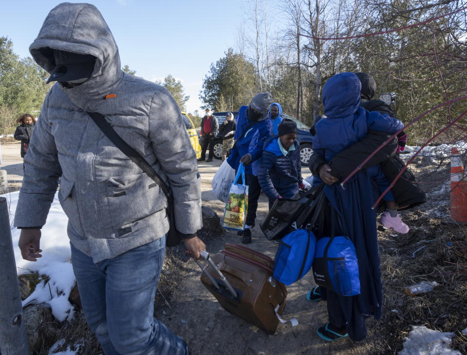 Asylum seekers cross the border at Roxham Road from New York into Canada on Friday, March 24, 2023, in Champlain, N.Y. The irregular border crossing will be closed permanently tonight at midnight. (Ryan Remiorz/The Canadian Press via AP)