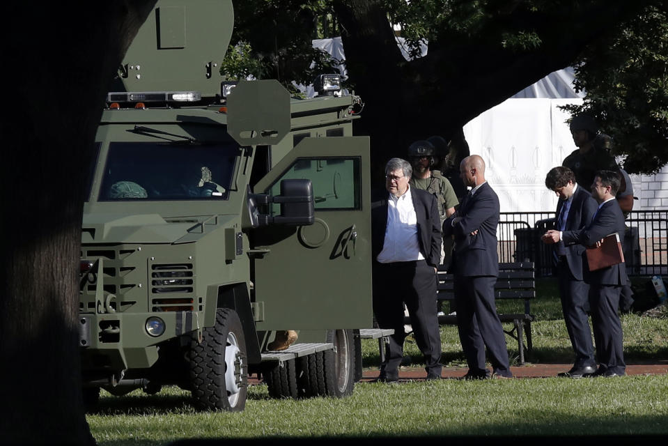 Attorney General William Barr, center, stands in Lafayette Park across from the White House as demonstrators gather to protest the death of George Floyd, Monday, June 1, 2020, in Washington. Floyd died after being restrained by Minneapolis police officers. (AP Photo/Alex Brandon)