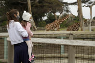 A woman holds a child while viewing giraffes at the San Francisco Zoo on Monday, July 13, 2020, in San Francisco. (AP Photo/Ben Margot)