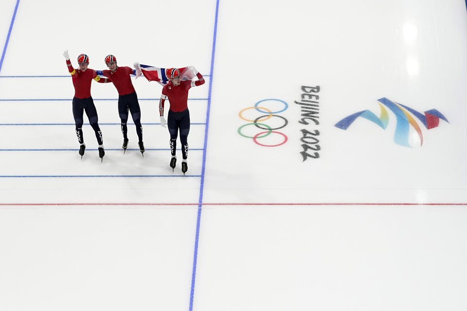 Team Norway's Peder Kongshaug, left, Sverre Lunde Pedersen and Hallgeir Engebraaten, right, sake with their country's flag after they won the gold medal in the speedskating men's team pursuit finals at the 2022 Winter Olympics, Tuesday, Feb. 15, 2022, in Beijing. (AP Photo/Ashley Landis)