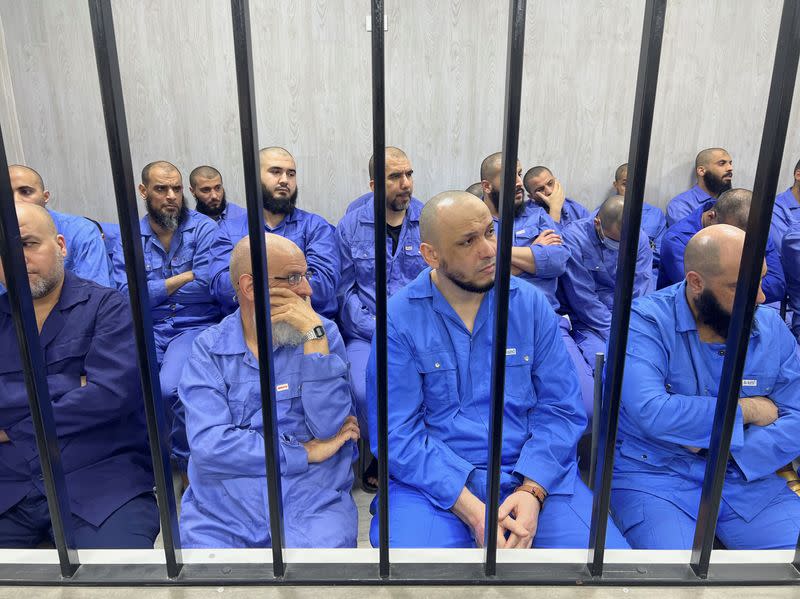 Suspects sit behind bars during a judgment sentence against 56 defendants accused of joining Islamic State group in the court in Misrata