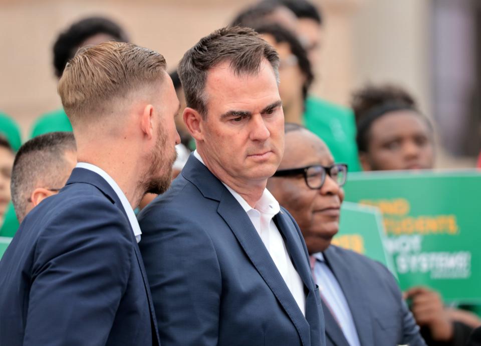 Gov. Kevin Stitt listens to Ryan Walters, Oklahoma state superintendent of public instruction, at a pro-school choice parents rally in March on the south steps of the Oklahoma Capitol.