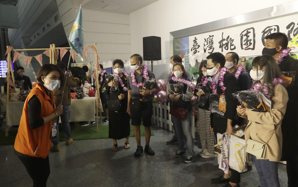 A tour guide commentary speaks to the first group of foreign travelers after their arrival at Taoyuan International Airport in Taoyuan, Northern Taiwan, Thursday, Oct. 13, 2022. Taiwan announced that it will end mandatory COVID-19 quarantines for people arriving from overseas beginning Oct. 13. The Central Epidemic Command Center announced that the previous weeklong requirement will be replaced with a seven-day self-monitoring period. (AP Photo/Chiang Ying-ying)