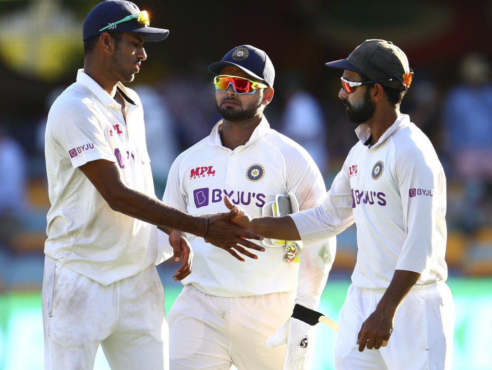 India's Washington Sundar is congratulated by his captain Ajinkya Rahane, right, as Rishabh Pant, centre, watches following play on the first day of the fourth cricket test between India and Australia at the Gabba, Brisbane, Australia, Friday, Jan. 15, 2021. (AP Photo/Tertius Pickard)
