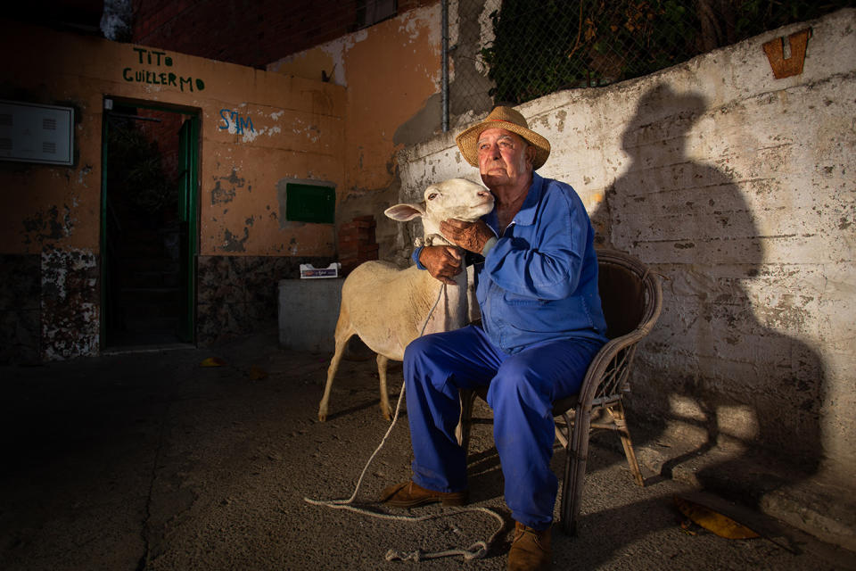 El jubilado, en la puerta de su casa, junto a una de sus ovejas, criadas como animales de compañí­a. Foto Fernando Ruso