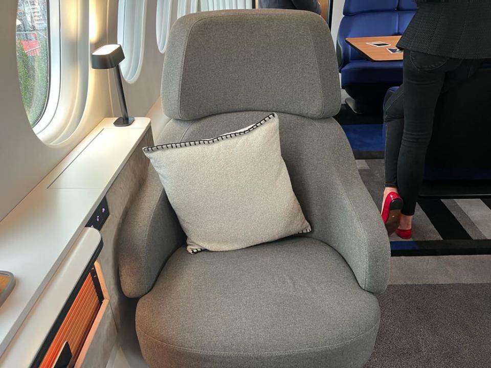 A grey chair with a white cushion on board a Falcon 10X