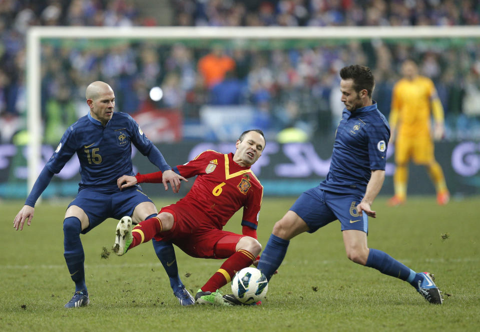 El jugador de la selección de España, Andrés Iniesta, centro, cae en la disputa de un balón en un partido contra Francia por las eliminatorias del Mundial el 26 de marzo de 2013 en París.(AP Photo/Christophe Ena, File)