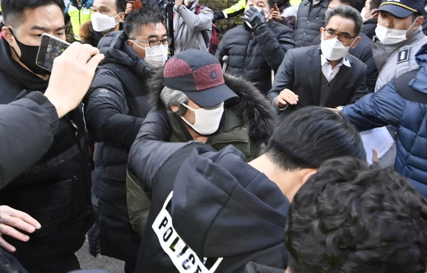 Cho Doo-soon, center, escorted by police officers, arrives home in Ansan, South Korea