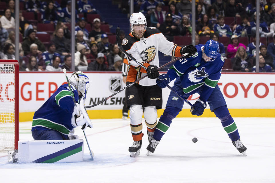 Anaheim Ducks' Brett Leason (20) checks Vancouver Canucks' Tyler Myers (57) in front of Canucks goalie Spencer Martin (30) during the second period of an NHL hockey game Thursday, Nov. 3, 2022, in Vancouver, British Columbia. (Ben Nelms/The Canadian Press via AP)