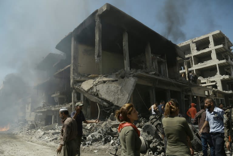 Onlookers gather at the site of a bomb attack in the northeastern Syrian city of Qamishli on July 27, 2016, which left at least 44 people dead, according to state media