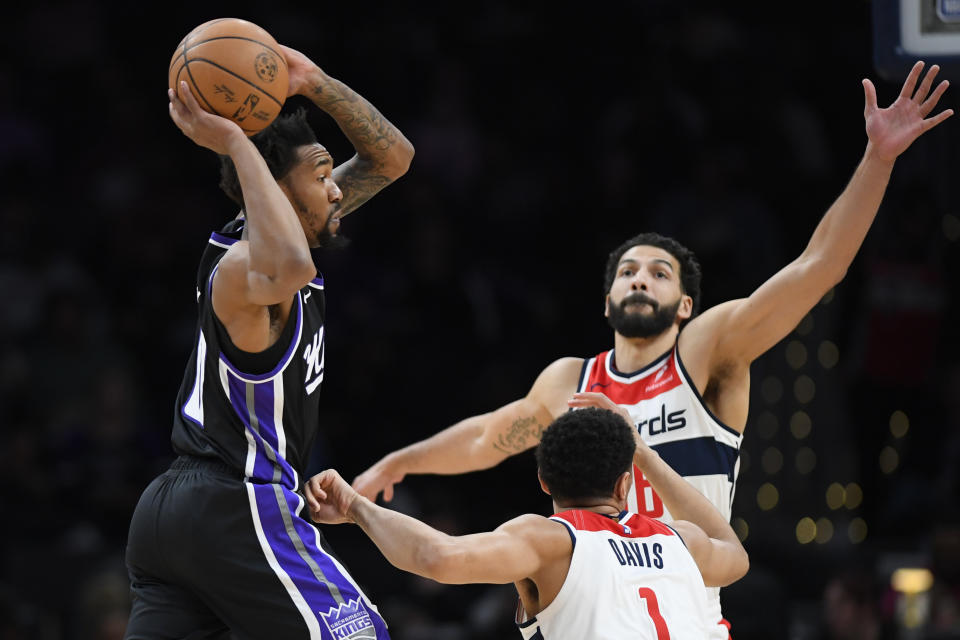Sacramento Kings guard Malik Monk, left, looks to pass the ball past Washington Wizards guard Johnny Davis (1) and forward Anthony Gill during the first half of an NBA basketball game Thursday, March 21, 2024, in Washington. (AP Photo/John McDonnell)
