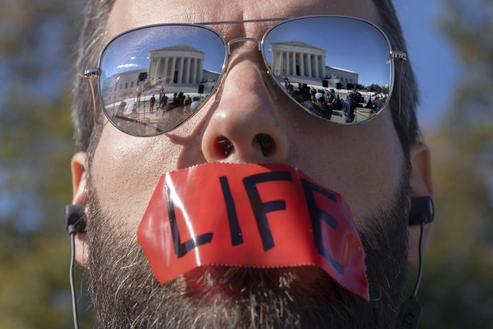 An anti-abortion activist wears tape saying "life" on his mouth at a rally outside the Supreme Court, Monday, Nov. 1, 2021, as arguments begin about abortion, at the court on Capitol Hill in Washington. (AP Photo/Jacquelyn Martin)