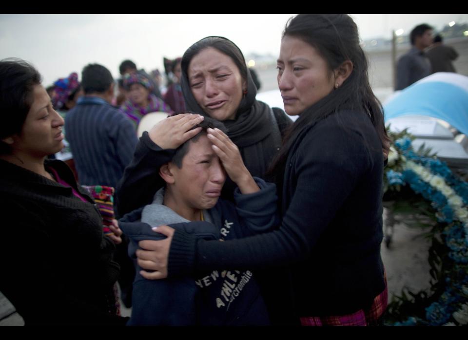 Relatives mourn next to the coffin containing the remains of Jose Yovanny Bocel at an Air Force base in Guatemala City , Wednesday, March 21, 2012. The remains of 11 Guatemalan citizens were repatriated from Mexico Wednesday, part of 193 bodies found in the northern Mexico Tamaulipas state in 26 mass graves in April 2011. (AP Photo/Rodrigo Abd)