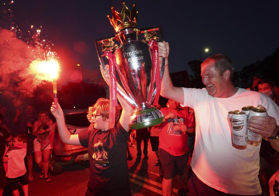 Two Liverpool fans hold a mock Premier League trophy aloft as the partying continued.