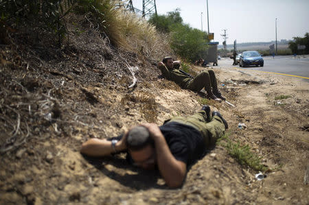 Israeli army reservists take cover as a siren sounds warning of incoming rockets near the southern city of Ashkelon July 23, 2014. REUTERS/Amir Cohen