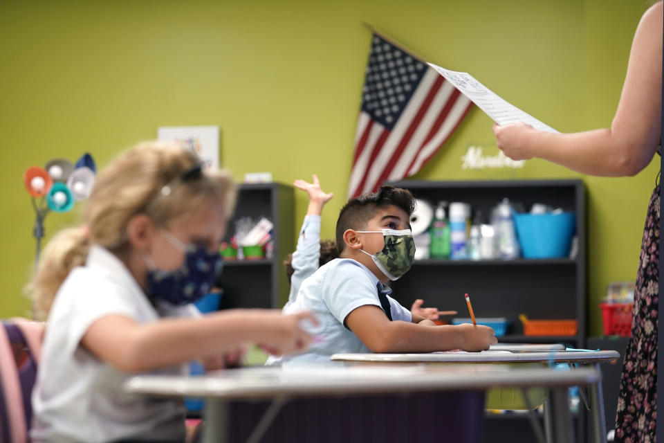 FILE - In this Aug. 23, 2021, file photo, a student listens to the teacher's instructions at iPrep Academy on the first day of school in Miami. Tumbling COVID-19 case counts have some schools around the U.S. considering relaxing their mask rules, but deaths nationally have been ticking up over the past few weeks, some rural hospitals are showing signs of strain, and cold weather is setting in. (AP Photo/Lynne Sladky, File)