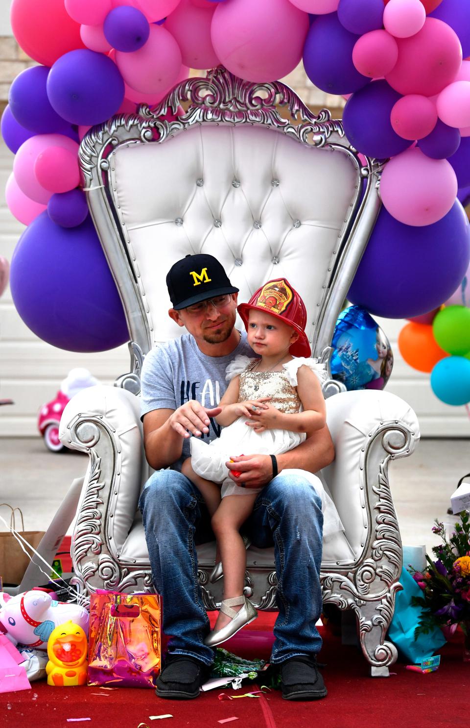 Tony Molina sits with his daughter Sienna in a donated throne on the family driveway during Tuesday’s parade in her honor.