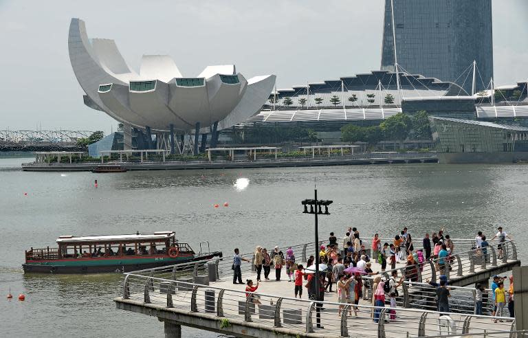 Tourists view the Marina Bay Sands resort hotel and casino from a pier at Merlion park in Singapore, on June 24, 2014