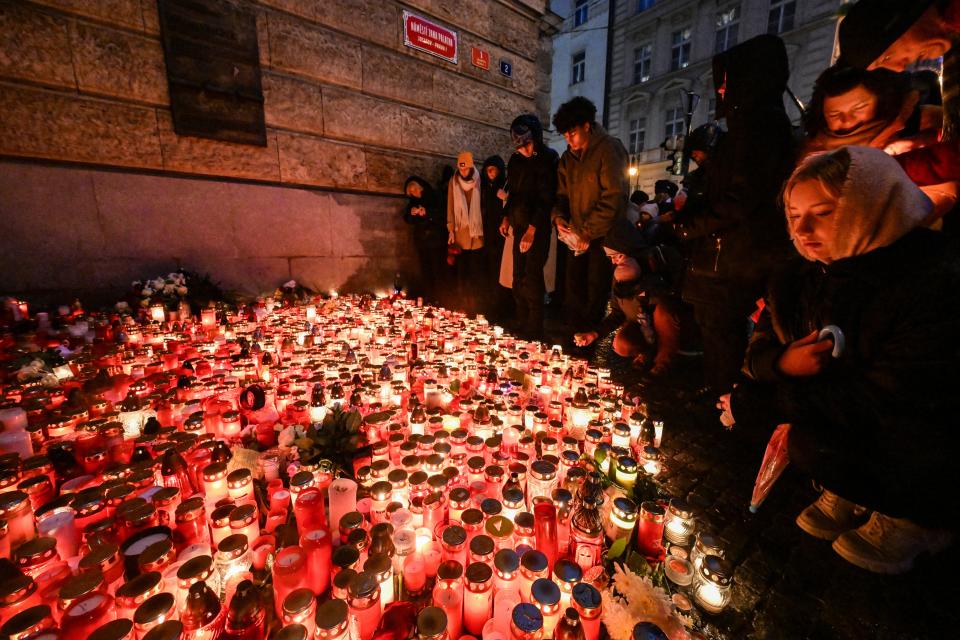 People place candles and flowers at a makeshift memorial for the victims of the Charles University shooting outside the Charles University in central Prague on Saturday (AFP via Getty Images)