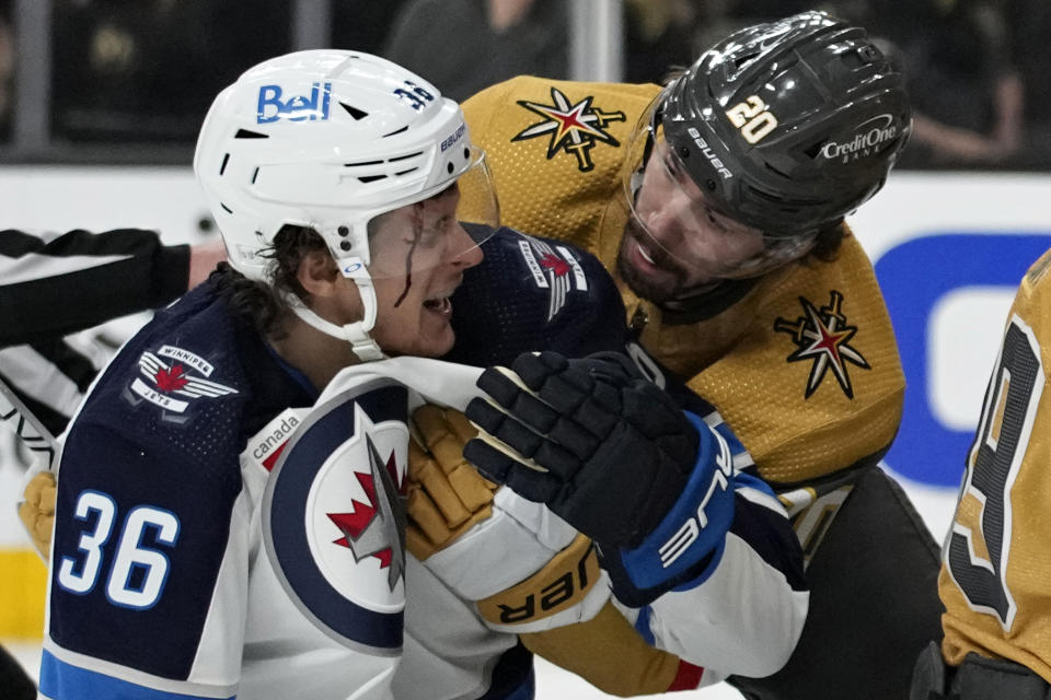 Vegas Golden Knights center Chandler Stephenson (20) helps Winnipeg Jets center Morgan Barron (36) after Barron cut his face on a skate during the first period of Game 1 of an NHL hockey Stanley Cup first-round playoff series Tuesday, April 18, 2023, in Las Vegas. (AP Photo/John Locher)