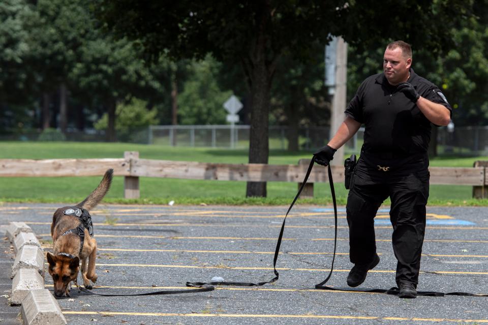 Framingham K9 officer Andrew Lewis watches as his partner, Murph, looks for shell casings during a demonstration at the fourth day of the Framingham Youth Police Academy at Loring Arena in Framingham, July 27, 2023.