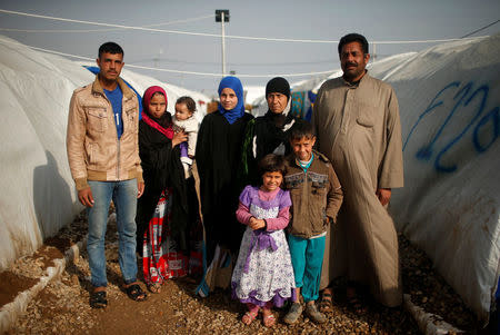 Displaced Iraqi Abed Ramadan (R), 37, poses for a photograph with his family at Hammam al-Alil camp south of Mosul, Iraq, March 29, 2017. Ramadan says his family fled while their district was being shelled. REUTERS/Suhaib Salem