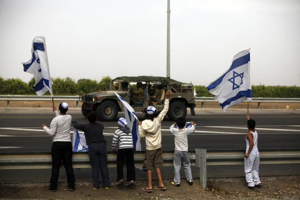Israeli children wave their national flag as they greet an army convoy passing on a road leading to the Israel-Gaza border near the southern Israeli town of Ofakim on November 17, 2012 in Israel. (Photo by Lior Mizrahi/Getty Images)