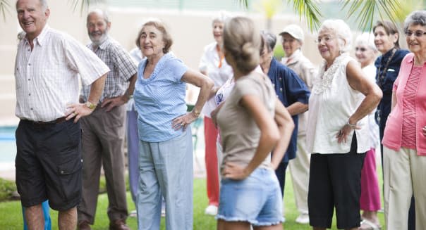 Large group of seniors exercising in retirement villa garden