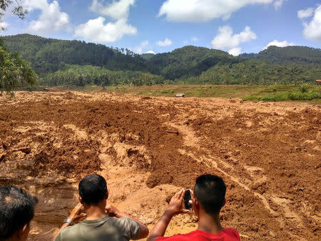 People take photos of a landslide in Brebes, Indonesia February 22, 2018, in this image obtained from social media. Aji Santoso/via REUTERS