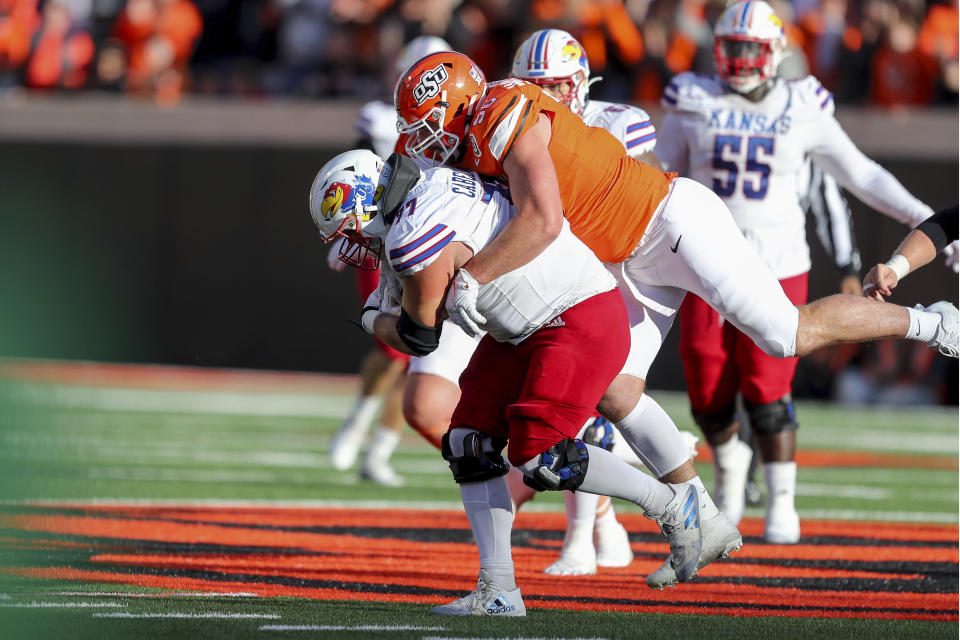 Kansas's Bryce Cabeldue (77) is tackled by Oklahoma State's Kody Walterscheid (96) after recovering a fumble during the second half of an NCAA college football game in Stillwater, Okla., Saturday, Oct. 14, 2023. (AP Photo/Mitch Alcala)