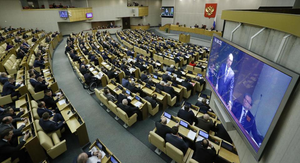 Members of the State Duma, lower parliament chamber, listen to Russian Foreign Minister Sergey Lavrov, seen on the screen, prior to voting during a plenary session in Moscow, Russia, Thursday, March 20, 2014. The Kremlin-controlled State Duma voted Thursday to allow Crimea to join Russia following a quick discussion in which members of the Kremlin-controlled chamber assailed the Ukrainian authorities. The merger needs to be rubber stamped by the upper house and signed by President Vladimir Putin, mere formalities expected to be completed by the end of the week. (AP Photo/Alexander Zemlianichenko)