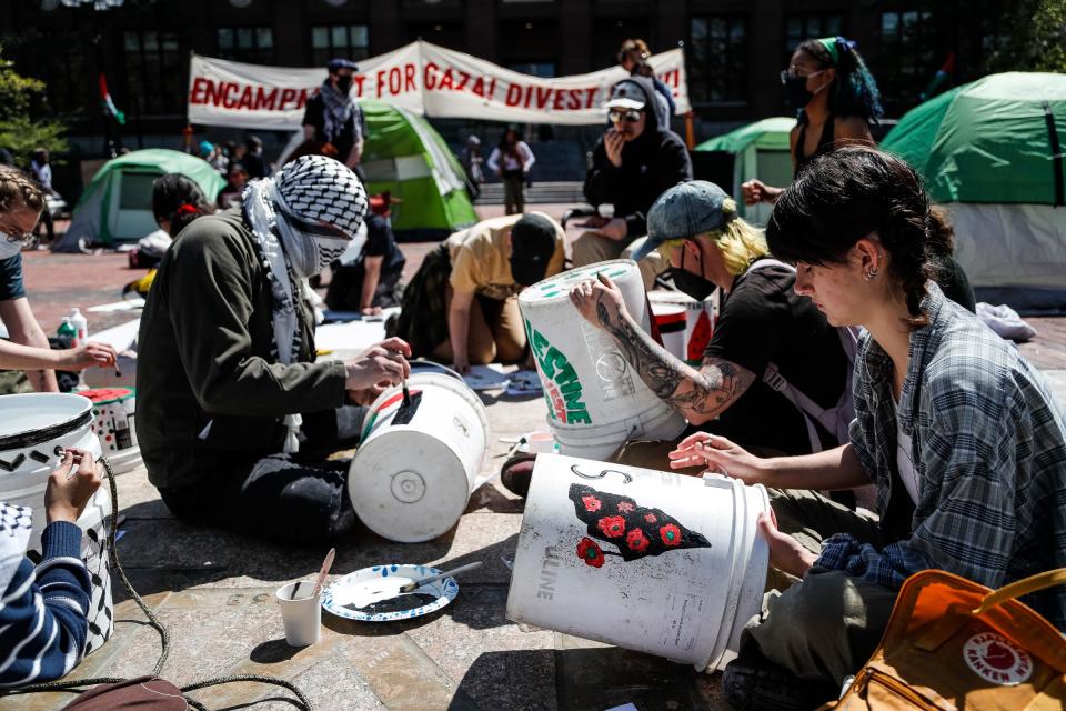 University of Michigan students paint Palestinian flags on buckets at an encampment in support of Palestinians at UM's Diag in Ann Arbor on Monday, April 22, 2024.
