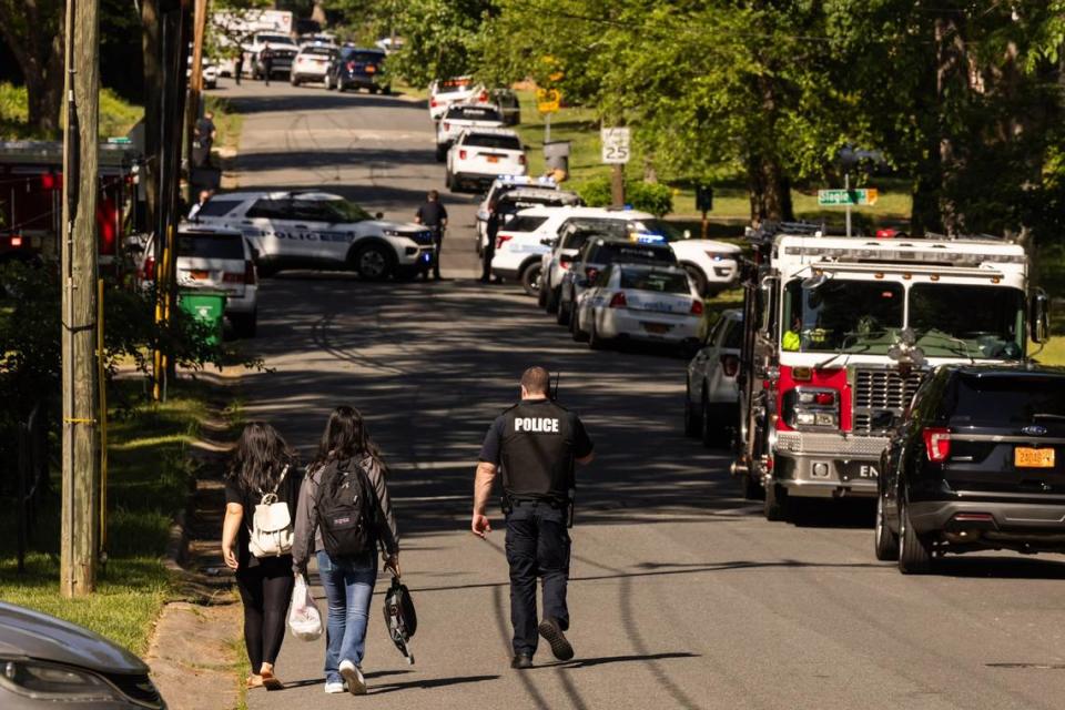 A CMPD officer, right, escorts two young girls trying to get home after school near the scene of a shootout on the 5000 block of Galway Drive in east Charlotte on Monday, April, 29, 2024.