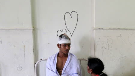 A relative sits next to the bed of a victim, who got injured in a fire at a temple at a hospital in Kollam in the southern state of Kerala, India, April 10, 2016. REUTERS/Sivaram V