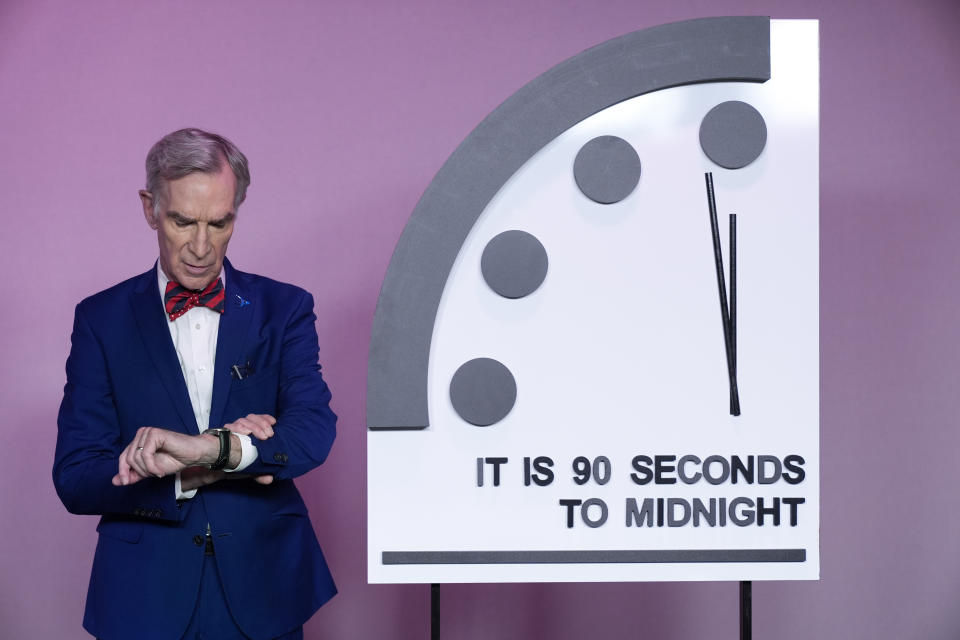 Science educator Bill Nye, looks at his watch next to the "Doomsday Clock," shortly before the Bulletin of the Atomic Scientists announces the latest decision on the "Doomsday Clock" minute hand, Tuesday, Jan. 23, 2024, at the National Press Club Broadcast Center, in Washington. This year, Jan. 2024, the clock will remain set to 90 seconds to midnight. (AP Photo/Jacquelyn Martin)