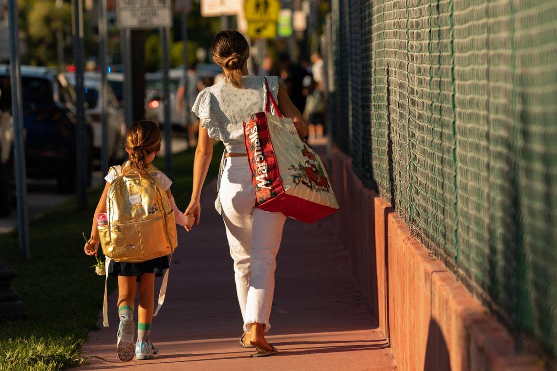 A student holds her mother’s hand as they walk to enter North Beach Elementary during the first day of school in Miami Beach on Aug. 17, 2022.