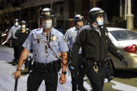 A Philadelphia police officer is covered with an unidentified red substance during a confrontation with protesters, Tuesday, Oct. 27, 2020, in Philadelphia. Hundreds of demonstrators marched in West Philadelphia over the death of Walter Wallace Jr., a Black man who was killed by police in Philadelphia on Monday. (AP Photo/Michael Perez)