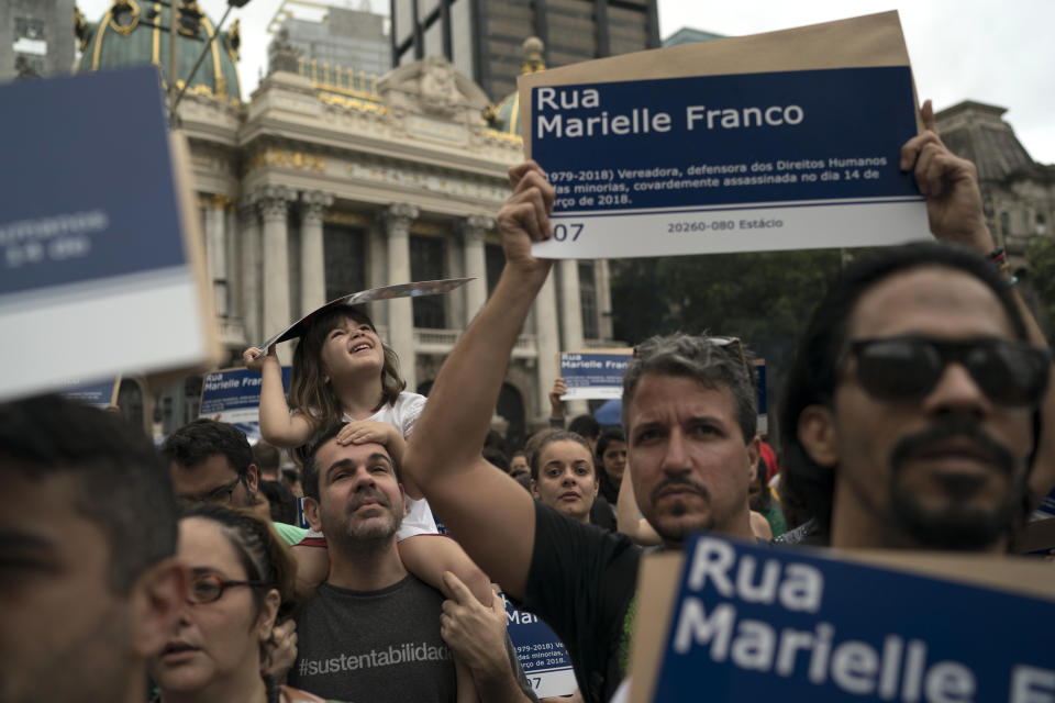 People hold street signs honoring slain councilwoman Marielle Franco as they mark the 7th month since her murder in Rio de Janeiro, Brazil, Sunday, Oct. 14, 2018. Franco supporters distributed a thousand street signs after a video on social media showed one being destroyed by two politicians with the right wing Social Liberal Party. (AP Photo/Leo Correa)
