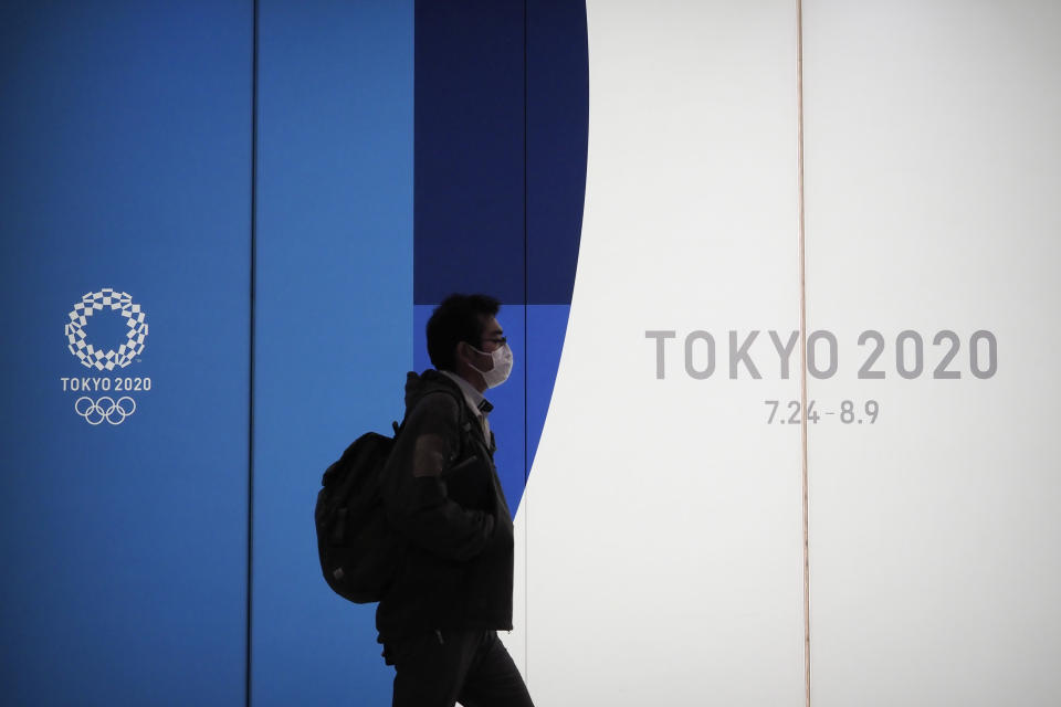 A man walks past a large display promoting the Tokyo 2020 Olympics in Tokyo, Friday, March 13, 2020. U.S. President Donald Trump's suggestion to postpone the Tokyo Olympics for a year because of the spreading coronavirus was immediately shot down by Japan's Olympic minister. For most people, the new coronavirus causes only mild or moderate symptoms. For some it can cause more severe illness. (AP Photo/Jae C. Hong)