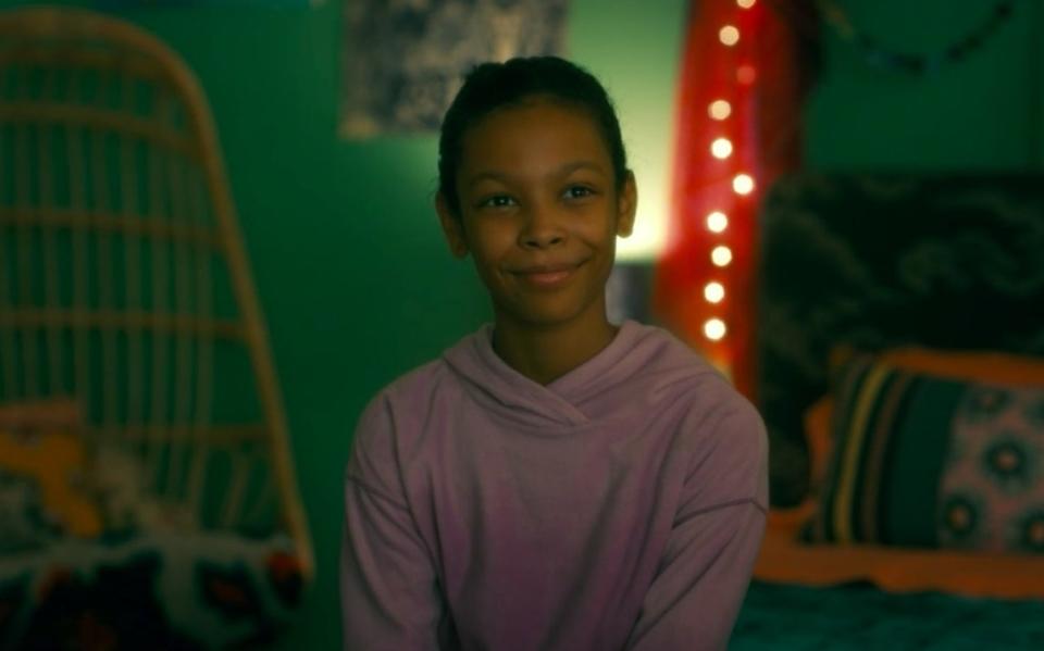 Abra sitting in her bedroom, smiling, in "Doctor Sleep"