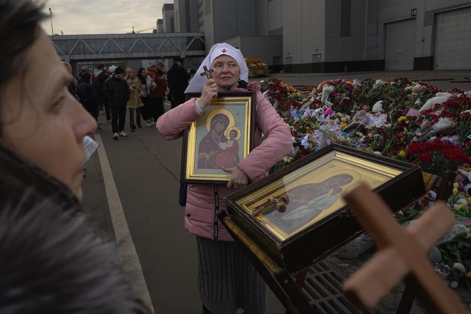 An Orthodox believer attends a service at a makeshift memorial in front of the Crocus City Hall on the western outskirts of Moscow, Russia, Tuesday, March 26, 2024. Russia is still reeling from the attack Friday in which gunmen killed 139 people in the Crocus City Hall, a concert venue on the outskirts of Moscow. Health officials said about 90 people remain hospitalized, with 22 of them, including two children, in grave condition. (AP Photo/Alexander Zemlianichenko)