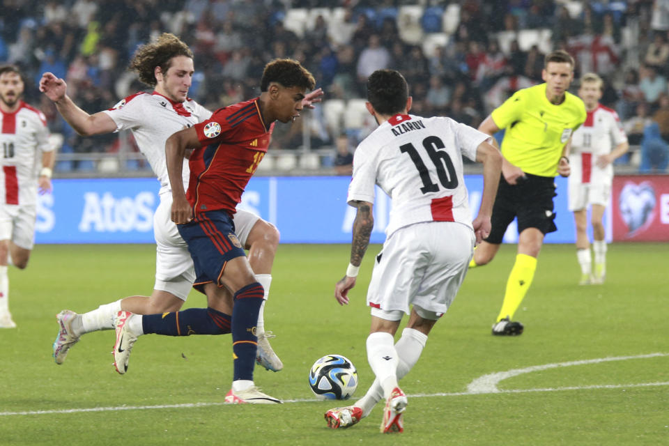 Spain's Lamine Yamal, centre, challenges for the ball with Georgia's Luka Gagnidze, left, during the Euro 2024 group A qualifying soccer match between Georgia and Spain at Boris Paichadze Dinamo Arena in Tbilisi, Georgia, Friday, Sept. 8, 2023. (AP Photo/Zurab Tsertsvadze)