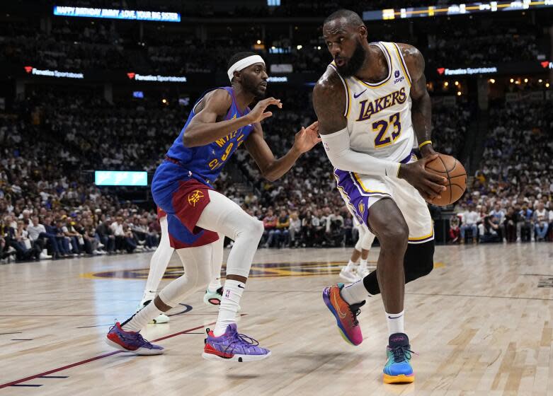 Los Angeles Lakers forward LeBron James (23) is pressured by Denver Nuggets forward Justin Holiday.